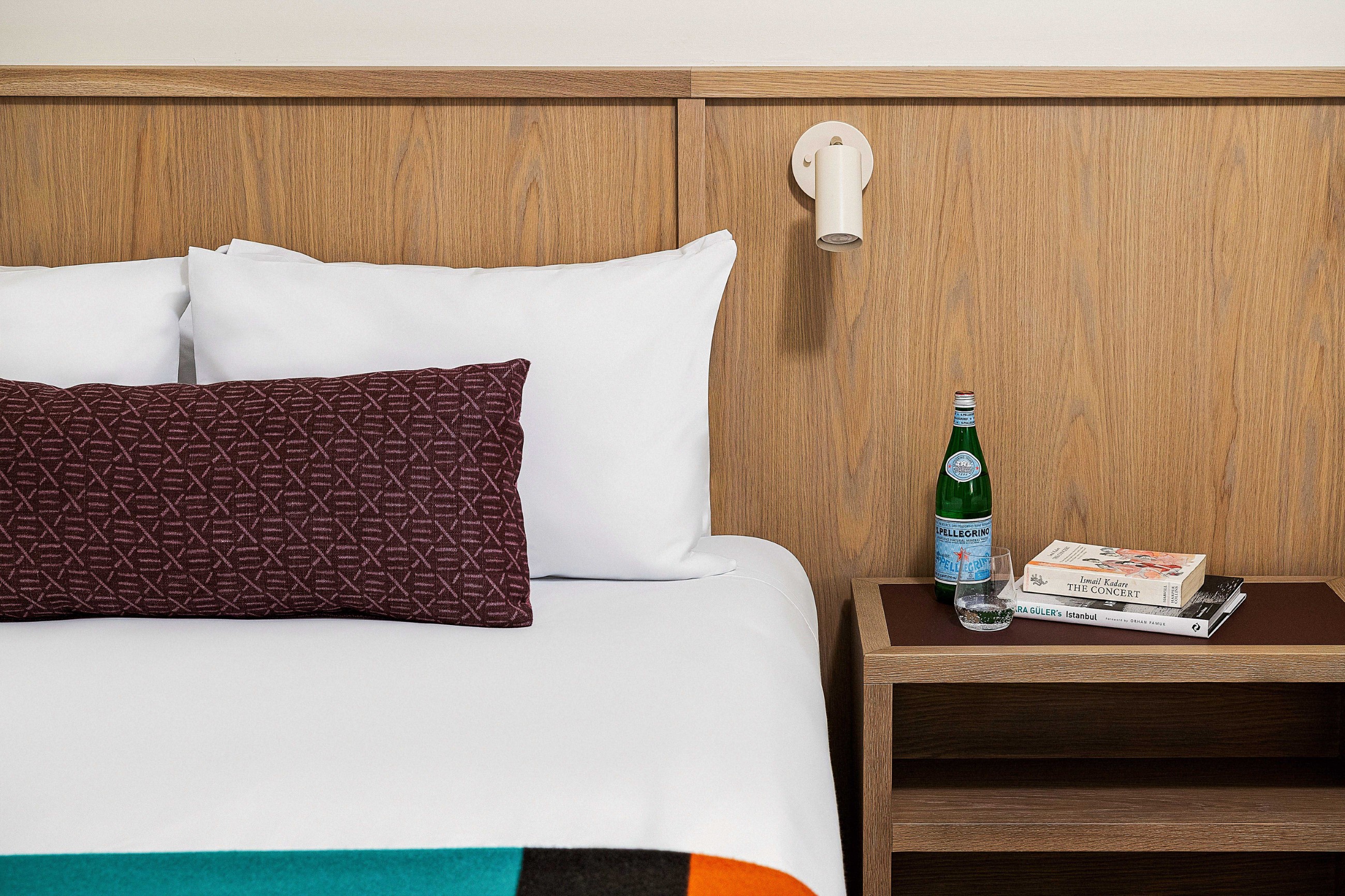 Queen bed with sparkling water and books on the side table